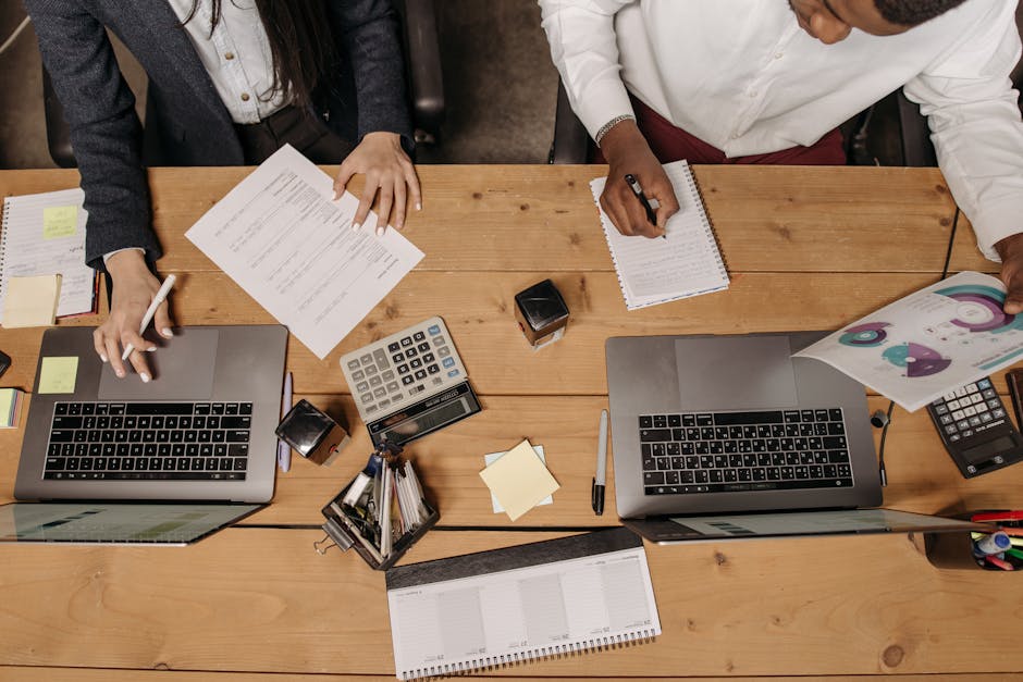 High-angle view of professionals working collaboratively with laptops and documents in an office.